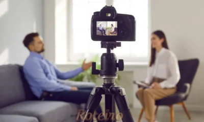 Jornalista entrevistando em uma sala com celular para trabalho multimídia