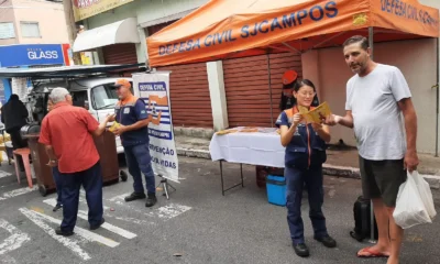 agentes da defesa civil em uma rua conversando com moradores
