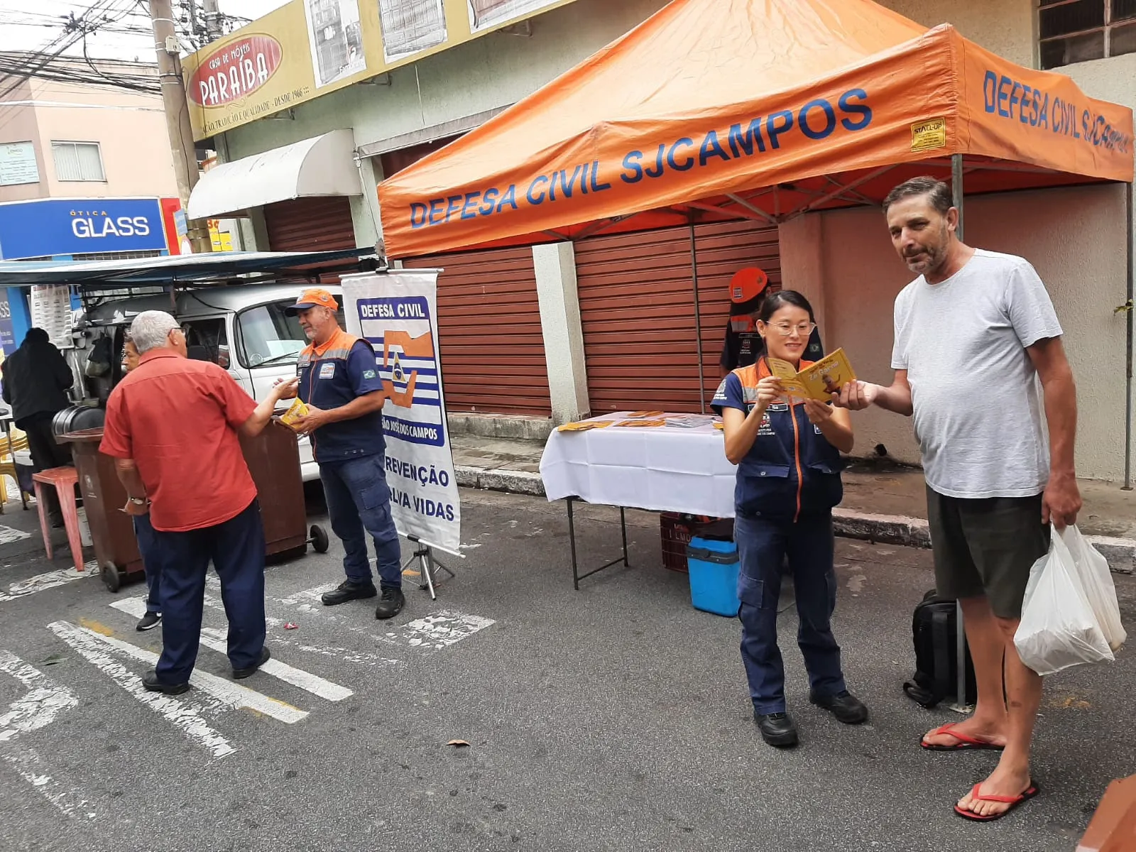 agentes da defesa civil em uma rua conversando com moradores