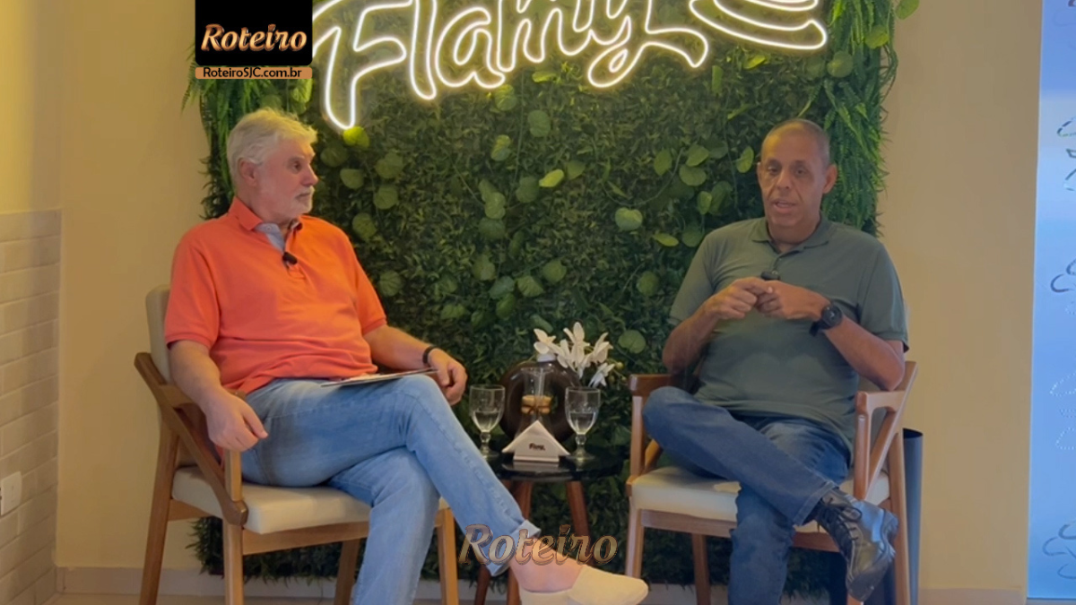 Glauco Guimarães e apresentador do RoteiroSJC, Marcio Marcondes, em entrevista descontraída na Flamy São José dos Campos. O locutor veste camisa escura e sorri durante o bate-papo sobre sua trajetória no rádio.