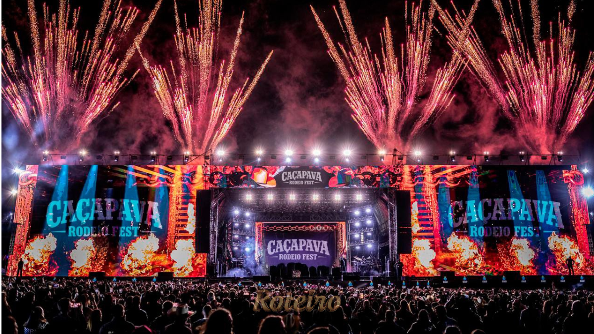 Estrutura gigante da arena e palco do Caçapava Rodeio Fest 2026, capturada à noite com iluminação cênica. A foto destaca a capacidade de público para os shows de Simone Mendes, Alok e Zé Neto & Cristiano, reforçando a importância do evento para o turismo e entretenimento regional no RoteiroSJC