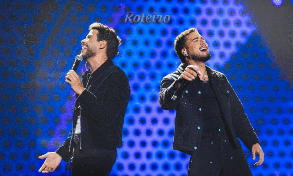 Dupla sertaneja Danilo e Davi cantando no palco, com iluminação de show