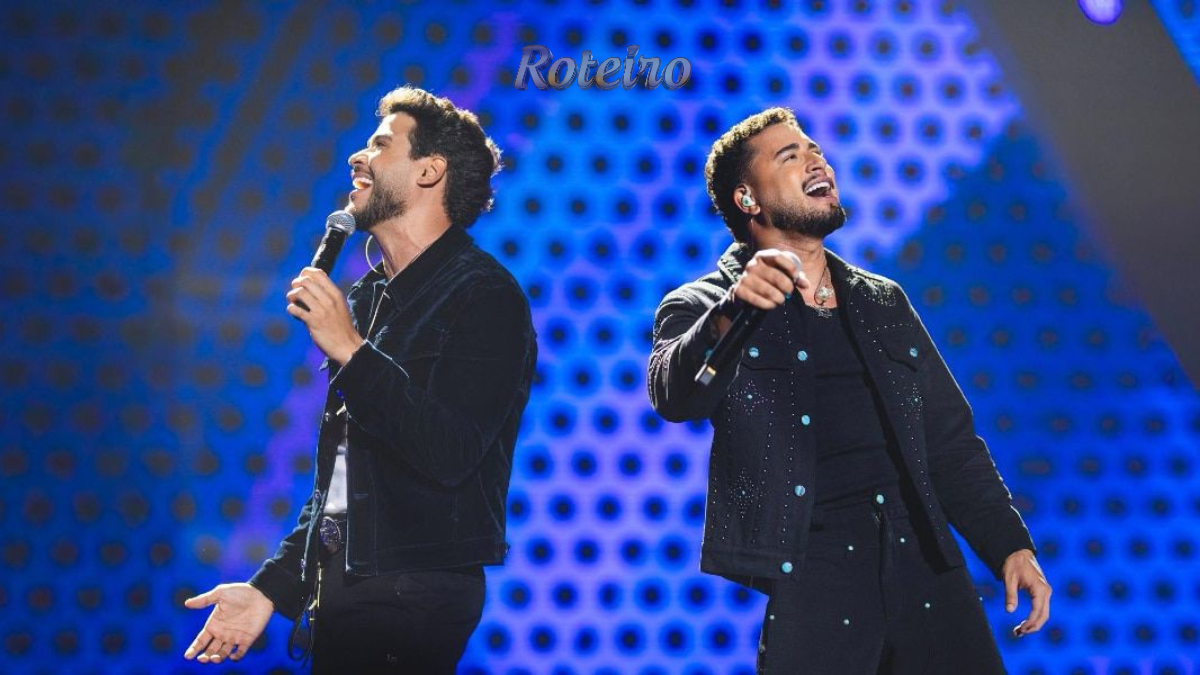 Dupla sertaneja Danilo e Davi cantando no palco, com iluminação de show