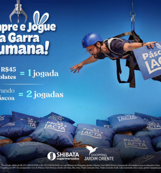 Pessoa suspensa por cabos de segurança sobre uma máquina gigante repleta de almofadas e brindes de chocolate no Shopping Jardim Oriente, promoção Garra Humana de Páscoa sjc