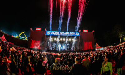 Vista panorâmica da arena lotada durante show na Jacareí Expo Agro do ano passado, destacando o palco iluminado, a grande estrutura de som e o público celebrando o maior rodeio do Vale do Paraíba.