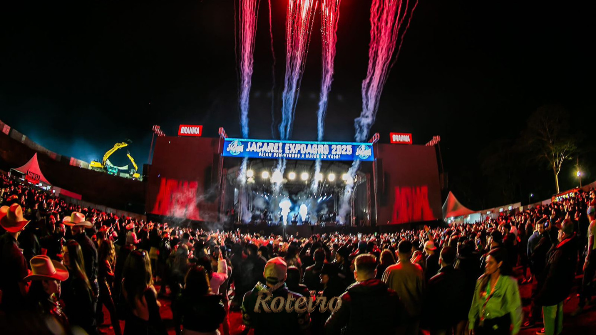 Vista panorâmica da arena lotada durante show na Jacareí Expo Agro do ano passado, destacando o palco iluminado, a grande estrutura de som e o público celebrando o maior rodeio do Vale do Paraíba.