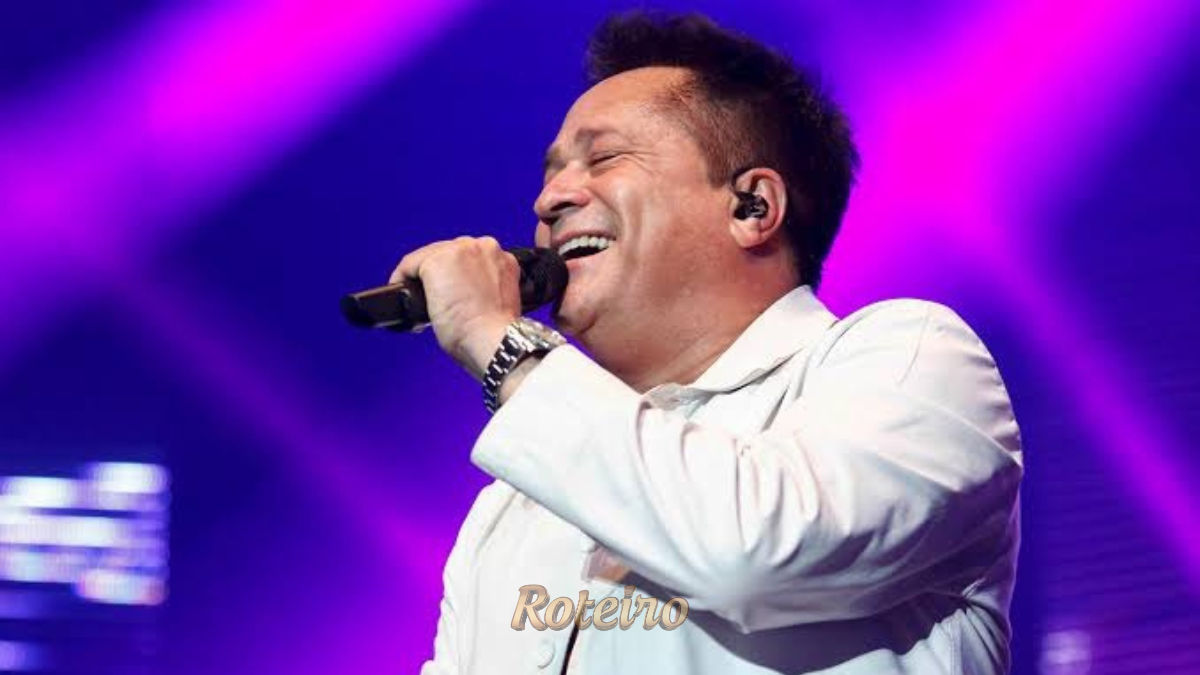 Fotografia de entretenimento mostrando o cantor sertanejo Leonardo no palco da Arena Farma Conde, em São José dos Campos. O artista aparece sorridente, segurando o microfone em um momento de interação com o público. Ao fundo, a estrutura de iluminação do show e a plateia lotada com milhares de fãs na arena, criando uma atmosfera de grande evento e celebração da música sertaneja no Vale do Paraíba