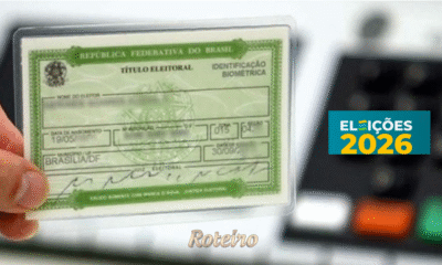 Mão segurando o titulo de eleitor, fundo uma urna eletronica e do lado direito a logo de Eleições 2026