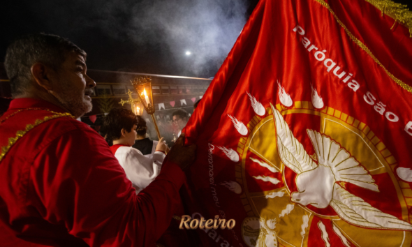 Procissão noturna da Festa do Divino Espírito Santo 2026 com bandeira da Paróquia São Benedito em Guararema SP — foto Warley Kenji Comunicação PMG