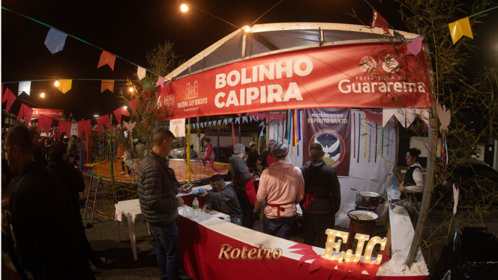 Barraca de bolinho caipira com bandeirinhas coloridas na quermesse da Festa do Divino Espírito Santo 2026 em Guararema SP — foto Warley Kenji Comunicação PMG