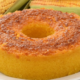 Bolo de milho cremoso assado em forma com furo, dourado e fofinho, com espigas de milho ao fundo — receita junina SJC foto Roteiro SJC
