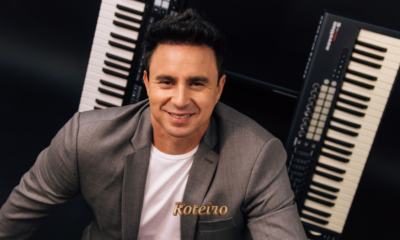 Allen Lima, músico integrante da Família Lima, sorridente em frente a dois teclados musicais, vestindo blazer cinza e camiseta branca em foto de divulgação do espetáculo Brasil em Teclas