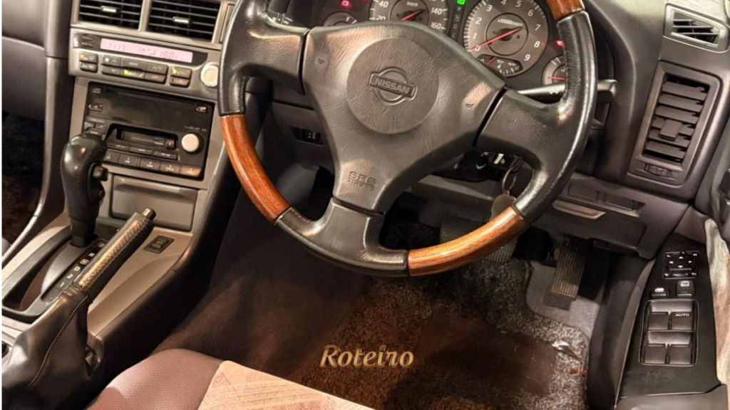 Interior do Nissan Skyline R34GT com volante de madeira e painel original no encontro de carros antigos em São José dos Campos