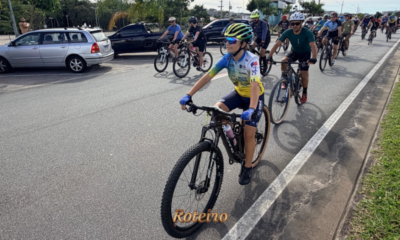 Grupo de ciclistas pedala em ciclovia de São José dos Campos durante o lançamento do programa Cicloturismo SJC, com destaque para ciclista jovem com capacete colorido e uniforme azul e amarelo na frente do pelotão. Foto: Claudio Vieira/PMSJC