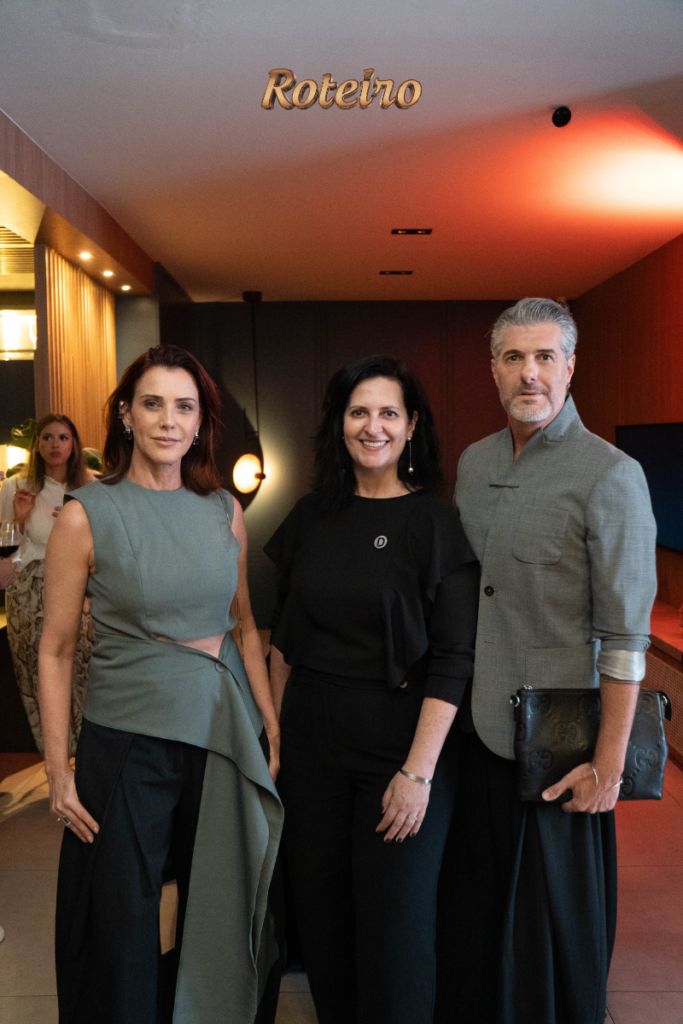 Três convidados posam no corredor do showroom durante o evento de lançamento da coleção 2026 da Dalmóbile em São José dos Campos