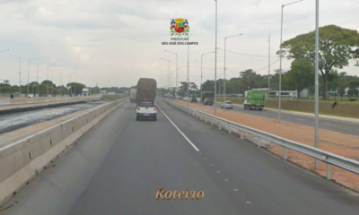 Pista da Rodovia Presidente Dutra em São José dos Campos com veículos em movimento, incluindo caminhão e carro de passeio, ladeada por postes de iluminação e área de obras na marginal esquerda