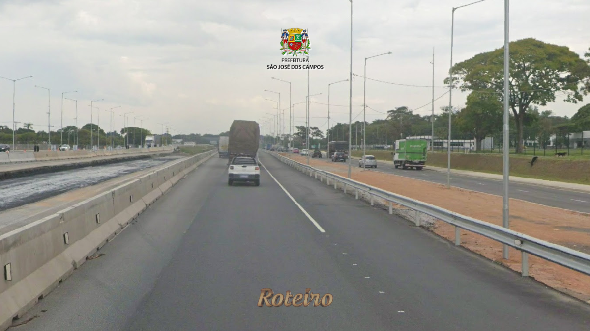 Pista da Rodovia Presidente Dutra em São José dos Campos com veículos em movimento, incluindo caminhão e carro de passeio, ladeada por postes de iluminação e área de obras na marginal esquerda