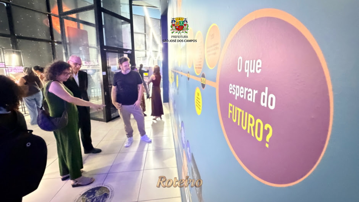 Visitantes observam painel interativo da exposição Raios! Mensageiros do Cosmos no Museu Interativo de Ciências de São José dos Campos, com destaque para o círculo roxo com a pergunta "O que esperar do FUTURO?"