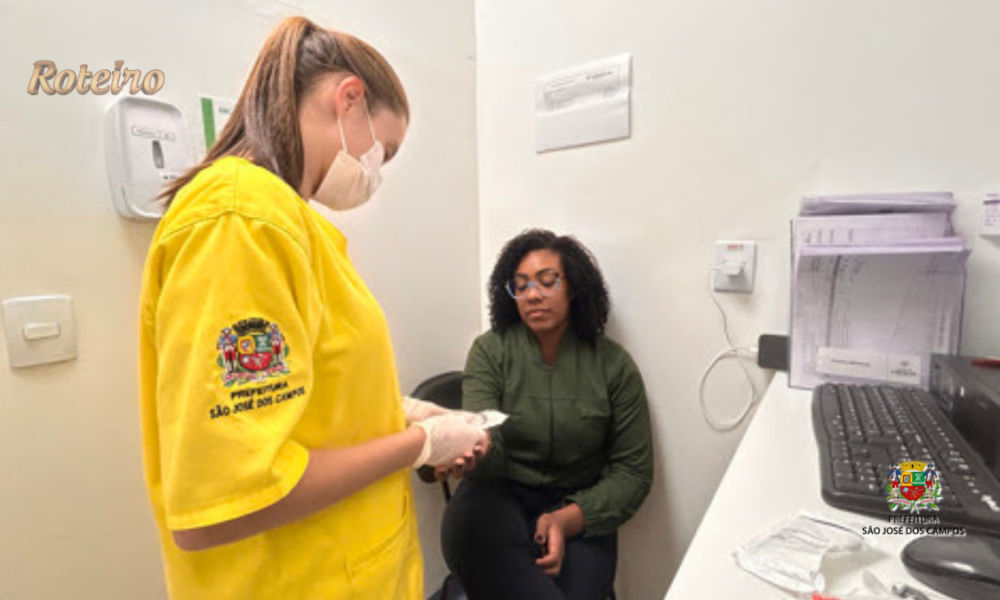 Profissional de saúde com uniforme amarelo e máscara da Prefeitura de São José dos Campos realiza atendimento a paciente sentada em consultório do Hospital de Clínicas Sul