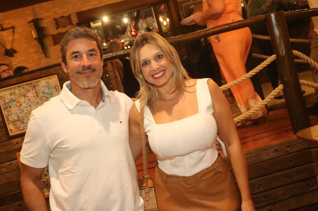 Casal sorri para a câmera no interior rústico da Fazenda da Vovó durante o 2º Jantar Solidário das Obras do Novo Caminho em São José dos Campos. Foto: @nandojrfotografo