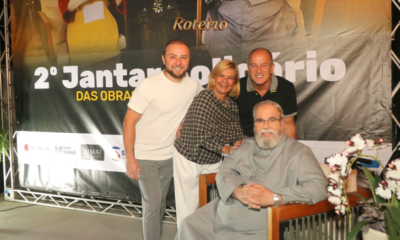 Padre Antônio Maria sentado ao centro com organizadores do evento em frente ao banner do 2º Jantar Solidário das Obras do Novo Caminho na Fazenda da Vovó, São José dos Campos. Foto: @nandojrfotografo