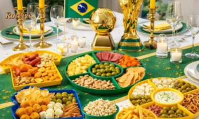 Mesa com petiscos variados e decoração verde e amarela para assistir os jogos da Copa do Mundo 2026 em casa — foto ilustrativa