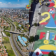 Montagem com vista aérea de São José dos Campos à esquerda, mostrando avenida principal e skyline da cidade, e à direita rua de bairro pintada com arte temática da Copa do Mundo FIFA 2026 nas cores verde, amarelo, azul e vermelho, com as letras FIFA 2026 em destaque. Foto: Divulgação/PMSJC