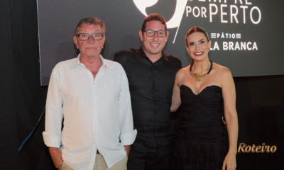 Três convidados posam para foto durante evento comemorativo dos cinco anos do Pátio Villa Branca em Jacareí, com painel "Sempre por Perto" do empreendimento ao fundo