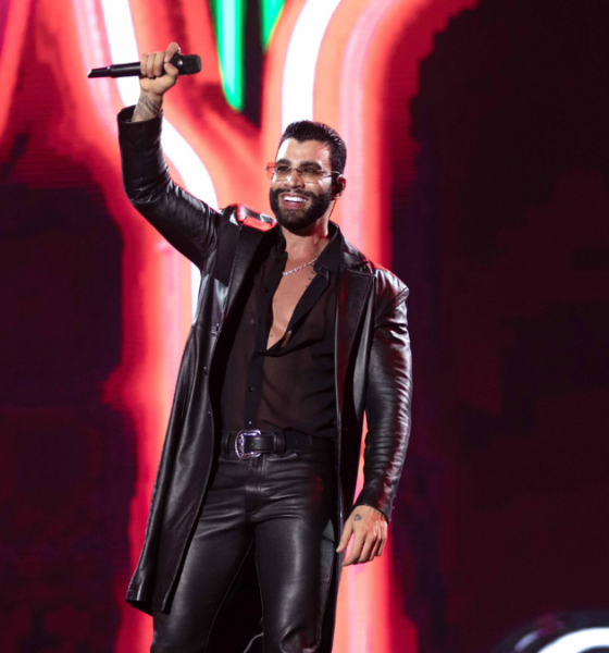 Cantor sertanejo no palco com microfone erguido e iluminação neon no Pinda Rodeio Fest 2026 — foto divulgação