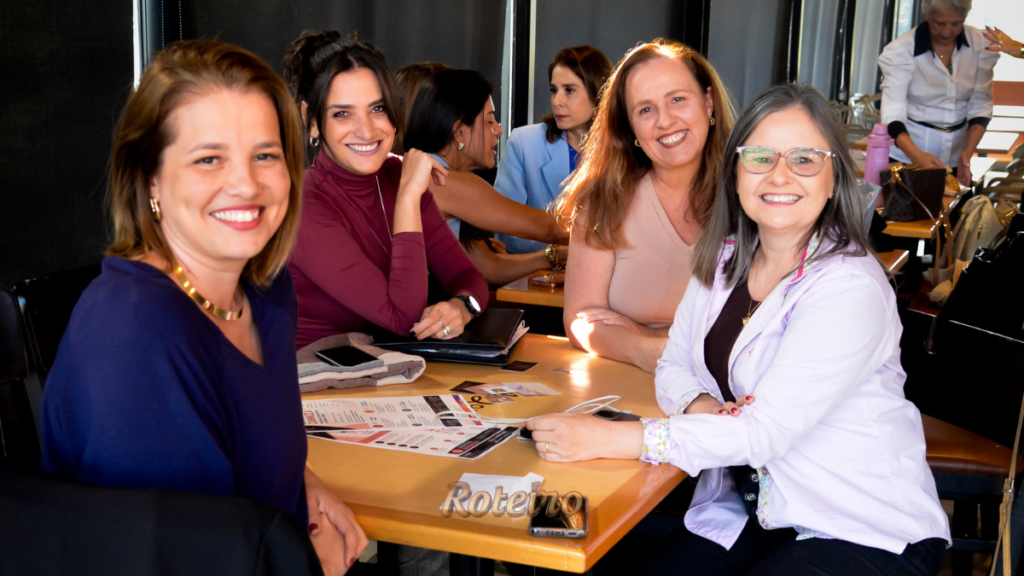 Grupo de mulheres sorri à mesa durante encontro da Comunidade Figueiras em São José dos Campos