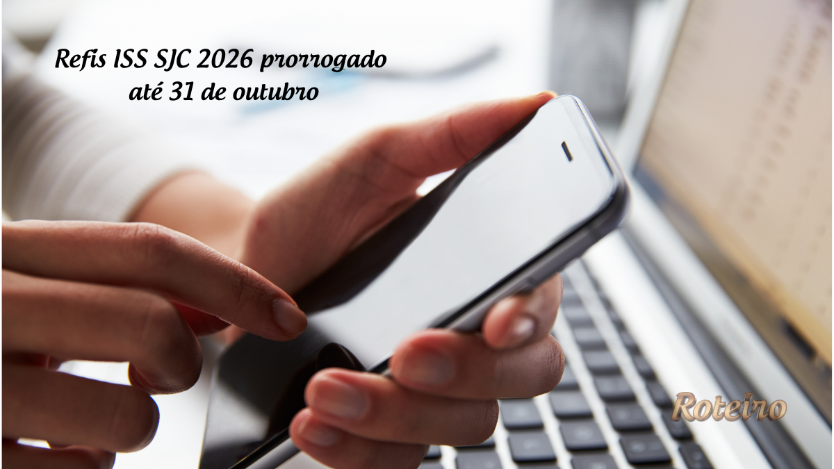 Refis ISS SJC 2026 prorrogado até 31 de outubro: mãos segurando celular em frente a notebook para adesão online