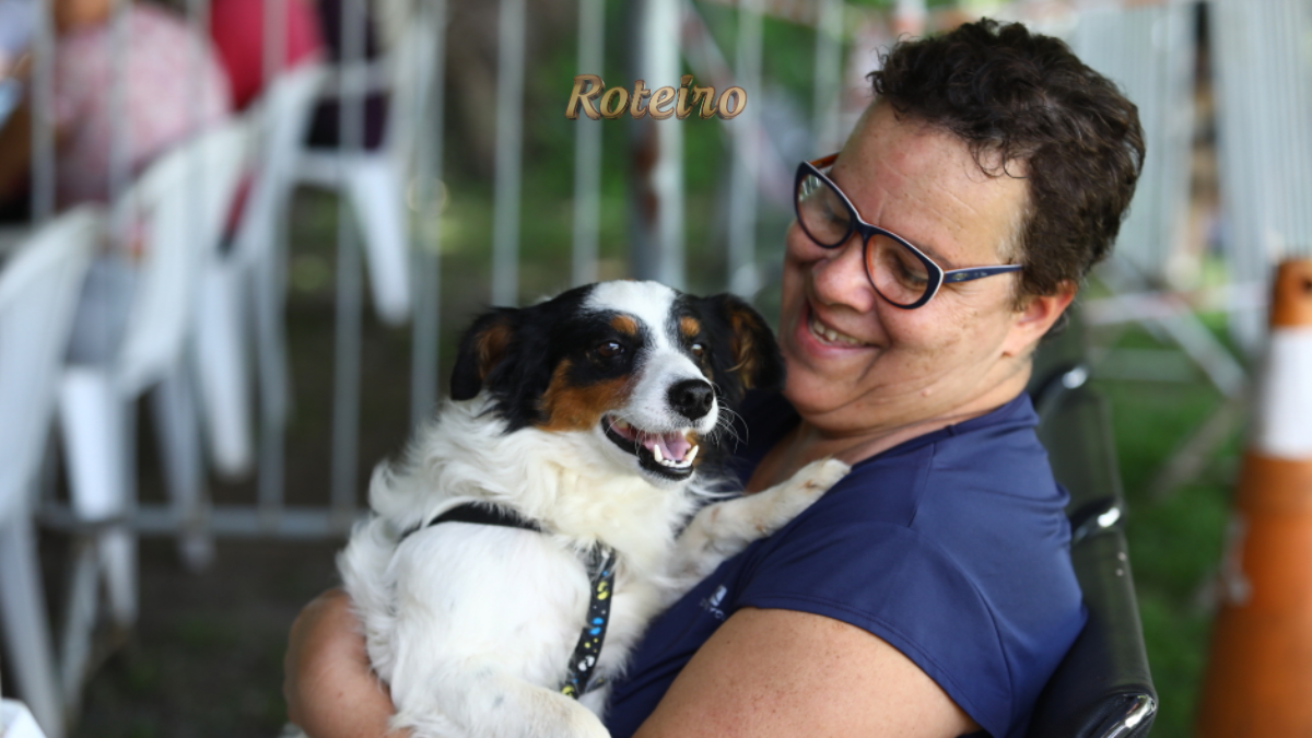 castração gratuita em SJC, tutora sorridente segura no colo cachorro preto, branco e caramelo