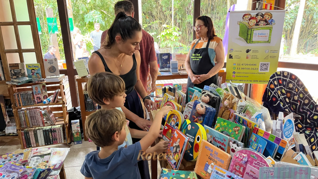 FLIG 2026 em Guararema, mãe e dois filhos escolhem livros infantis em banca da festa