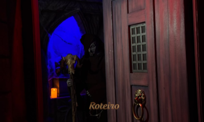 Halloween Castelo do Terror: personagem encapuzado com máscara de caveira e cajado surge atrás de porta de madeira no percurso da atração