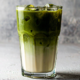 receita de matcha latte gelado em copo alto com gelo e camadas de matcha e leite