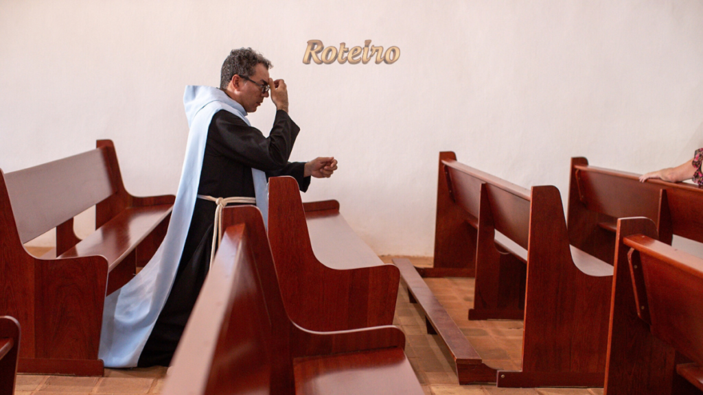 roteiro religioso em Guararema – frade em oração entre os bancos de madeira de igreja histórica